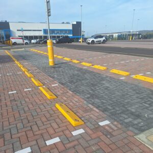 Yellow polymer car wheel stops and lamp post protector installed in commercial car park bays
