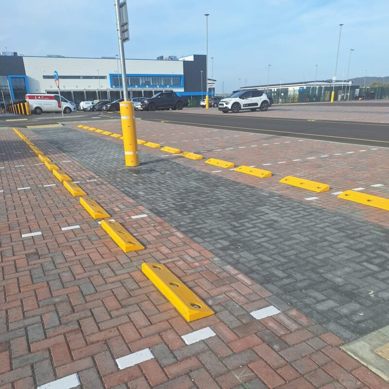 Yellow polymer car wheel stops and lamp post protector installed in commercial car park bays