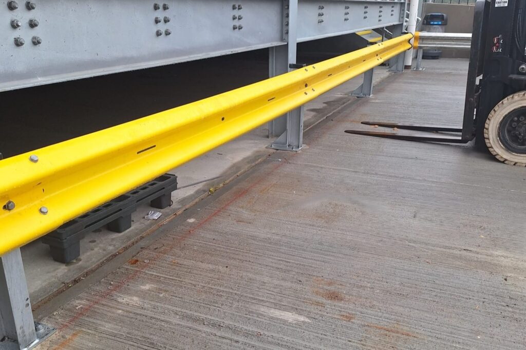 Powder‑coated Yellow Armco Barrier With Black‑and‑yellow Polymer Ends And Handrail In The Background V4